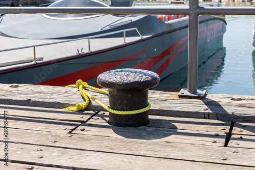 Heavy metal mooring bollard with yacht secured with yellow rope stands on pier of Larnaca Marina in Larnaka in Cyprus