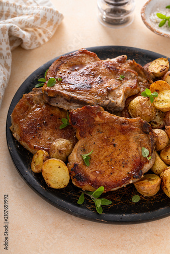 Pork chops on a bone grilled or sauteed served with roasted potatoes on a plate