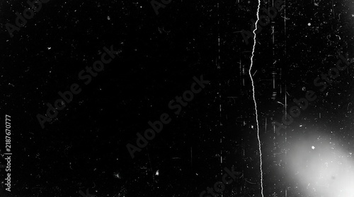 Monochrome film distress overlay with vintage dust and grain texture featuring a vertical crack and light leak, ideal for analog cinema aesthetic in video editing and photo design.
