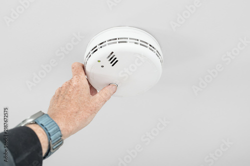 Obraz na płótnie Handyman seen doing a weekly test of a combine smoke and carbon monoxide tester in a home hallway