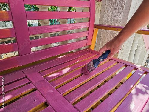 Painting a wooden bench seat pink with a brush