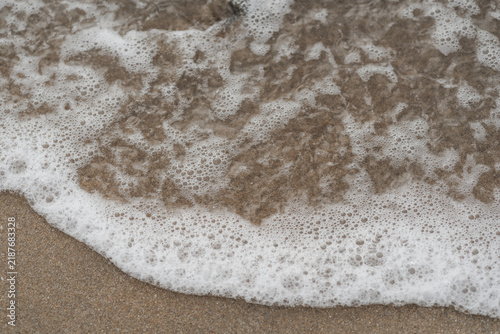 Fotografie Espuma de mar densa cubriendo la arena en primer plano