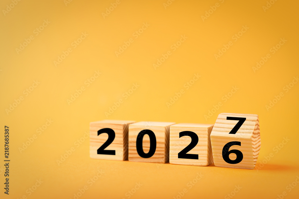 Obraz premium New Year 2027. Wooden cube flipping changing number from six to seven against orange background