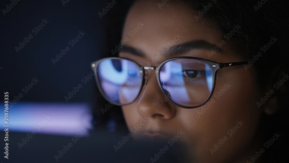 Fototapeta premium Woman Focused on Computer Screen with Glasses Reflection at Night