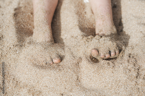 Pies pequeños hundidos en la arena de playa