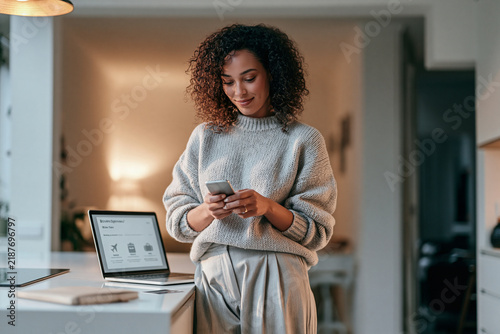 Young woman using smartphone while working at home office desk  