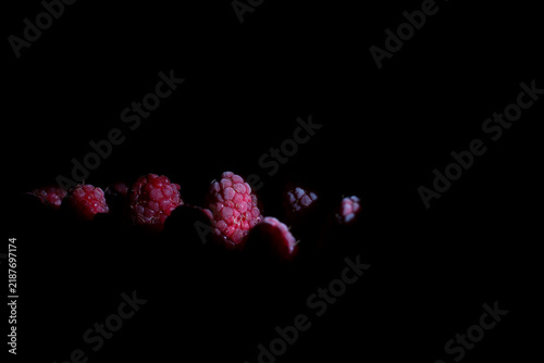 Fresh raspberries in dramatic light with copy space