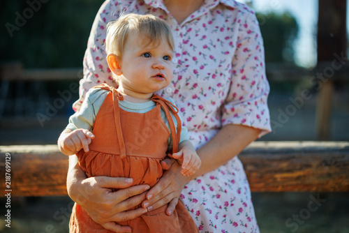 Woman holding a small child in an orange jumpsuit outdoors