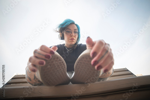Canvastavla Cool gen z alternative woman with blue hair holding her shoes with copy space