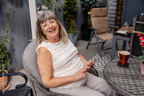 Картината върху платно happy older woman laughing in garden chair on a warm summer afternoon