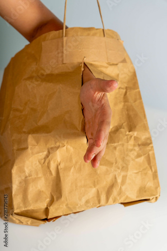 Bild auf Leinwand Hand reaching out from a brown paper bag in a simple indoor setting