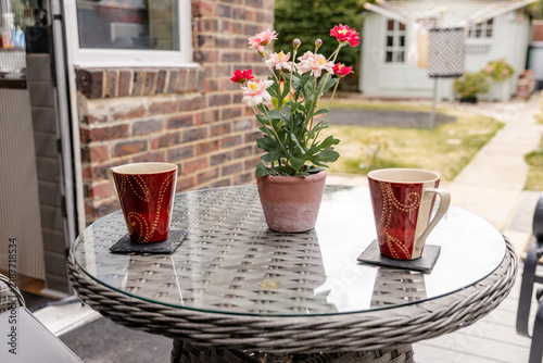 Bild auf Leinwand two cups of tea on a garden table with potted flowers on sunny patio