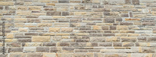 Beige brown stacked stone veneer wall surface texture background with blocks
