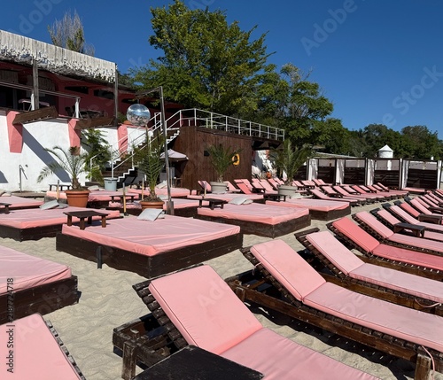 Beach resort with pink lounge chairs and tropical landscaping in sunlight