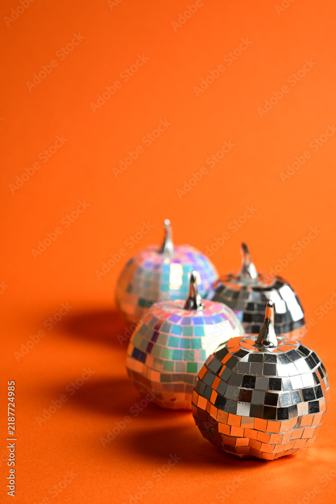 Naklejka premium decorative disco ball pumpkins arranged on orange background with reflective tiles for autumn and party theme