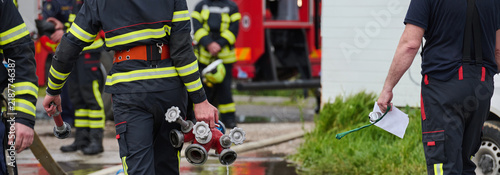 Firefighters Working Together Carrying Hoses And Hydrant Manifold Near Fire Truck During Emergency Response