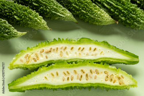 Foto A half-cut bitter melon (Momordica charantia) with whole bitter melons in the background, set against a pastel green backdrop