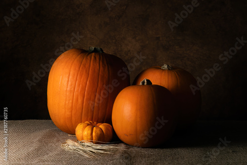Autumn still life with four orange pumpkins on burlap
