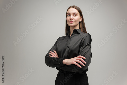 Quadro su tela Confident woman in a sleek black shirt posing with arms crossed in a minimalist