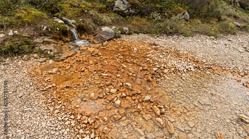 Rust-colored mineral deposits following a shallow gravel seep