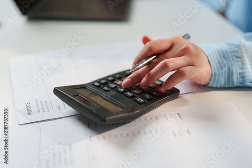 Close-up Accountant verifying financial billing statements with a pen and calculator, certified public accountant services, corporate tax compliance, forensic accounting, statutory audit diligence