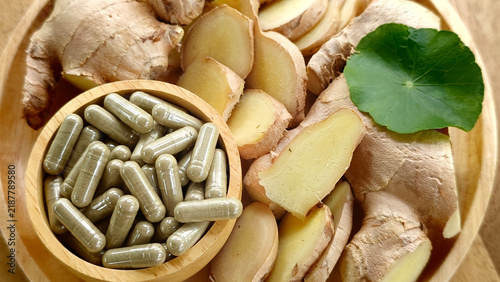 Fotografía Ginger capsules herb in a wooden cup and ginger rhizomes.