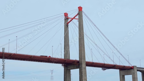 Wide angle video of a massive cable-stayed bridge crossing a wide river under an overcast sky
