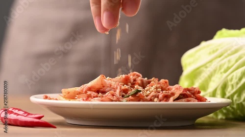 Hand sprinkling roasted sesame seeds on Kimchi Napa cabbage, Korean side dish (Banchan), Slow motion shot