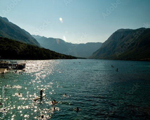 Принти на полотні People enjoy recreational activities like stand-up paddleboarding and swimming in the scenic Lake Bohinj, Slovenia, taking advantage of the warm summer weather and stunning alpine views