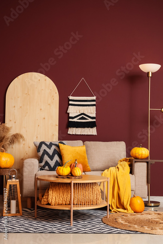 Interior of stylish living room with grey sofa, table and pumpkins