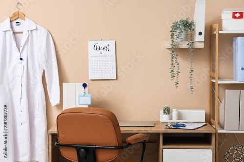Doctors workplace with laptop and flip calendar on beige wall in medical office
