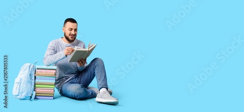 Fotografía Education and lifelong learning, young man reading a book with a stack of textbo