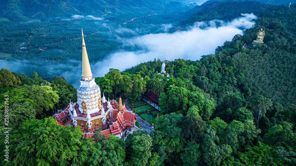 Obraz premium Peaceful sunrise landscape featuring Wat Bang Riang, tropical mountains, forest, clouds, and atmospheric morning mist in Thap Put, Phang Nga, Thailand.