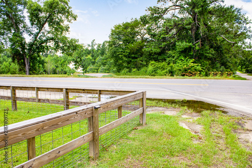 Obraz na plátně Wooden fence alongside country asphalt road with grassy verge landscape countrys