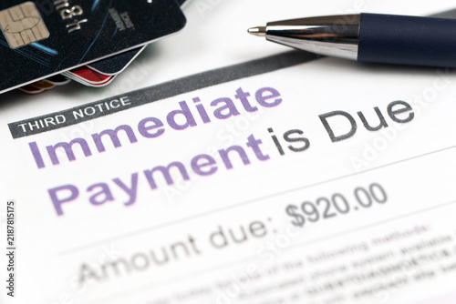 Medical billing statement showing immediate payment is due, with a pen and credit cards. Highlights financial stress, healthcare costs, debt, and overdue payments.