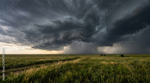 Severe storm cloud with heavy rain over green field
