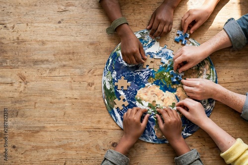 A close up of children's hands grasping puzzle pieces on a table, representing teamwork for International Children's Day