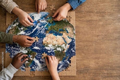 Children's hands holding colorful puzzle pieces on a wooden table, symbolizing unity and collaboration for World Children's Day