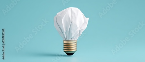 Creative concept of a crumpled paper light bulb on a blue background representing innovative ideas and sustainability
