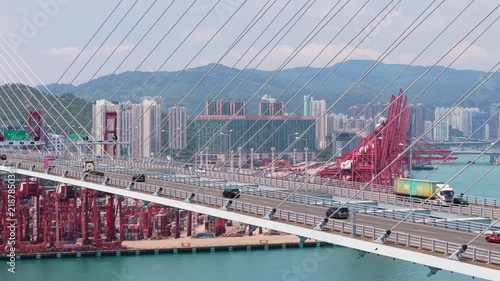 Stunning aerial view of vehicle traffic, including trucks and cars, crossing the impressive Stonecutters Bridge, a major highway connecting different parts of the vibrant city of Hong Kong