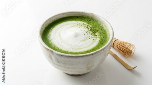 Ceramic bowl filled with green matcha latte featuring white foam swirls and a bamboo whisk nearby green tea latte art hot beverage japanese tea powdered tea cup of tea white background