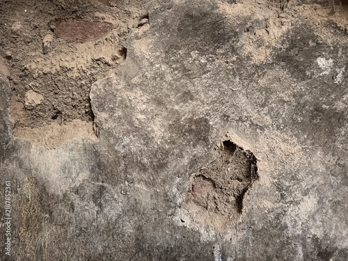 Close-up of old distressed concrete wall with peeling plaster, cracked cement texture, and exposed weathered background.