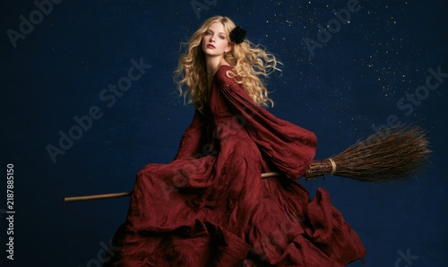 Girl in red dress flying on broom over dark sky with stars