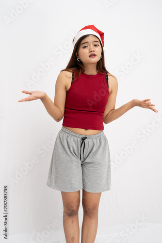 Quadro su tela Confused Young Woman Wearing A Holiday Seasonal Hat And Red Sleeveless Top With
