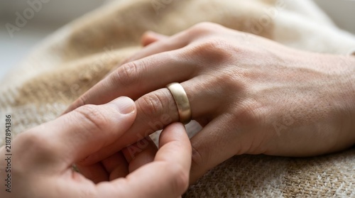 Close Up of Hands with Wedding Ring Holding Each Other on Soft Beige Blanket