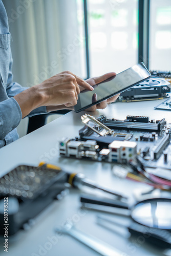 Asian IT engineer man using tablet AI helping fixing mainboard