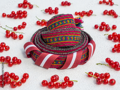 Konstfotografi Handwoven traditional Latvian ethnographic belt rolled up and decorated with a L