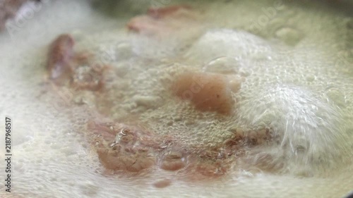 4K Close up meat pieces boiling in simmering water with foam and bubbles, cooking preparation process for soup stock and Asian broth recipe concept.