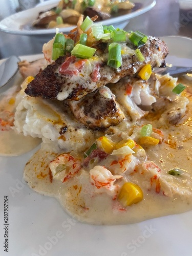 Blackened Fish over Creamy Grits with Crawfish Sauce and Corn Maque Choux