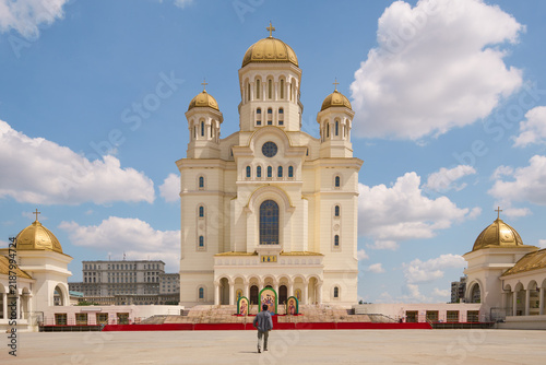 Front view of the majestic People's Salvation Cathedral with its golden domes under a blue sky in Bucharest, Romania.